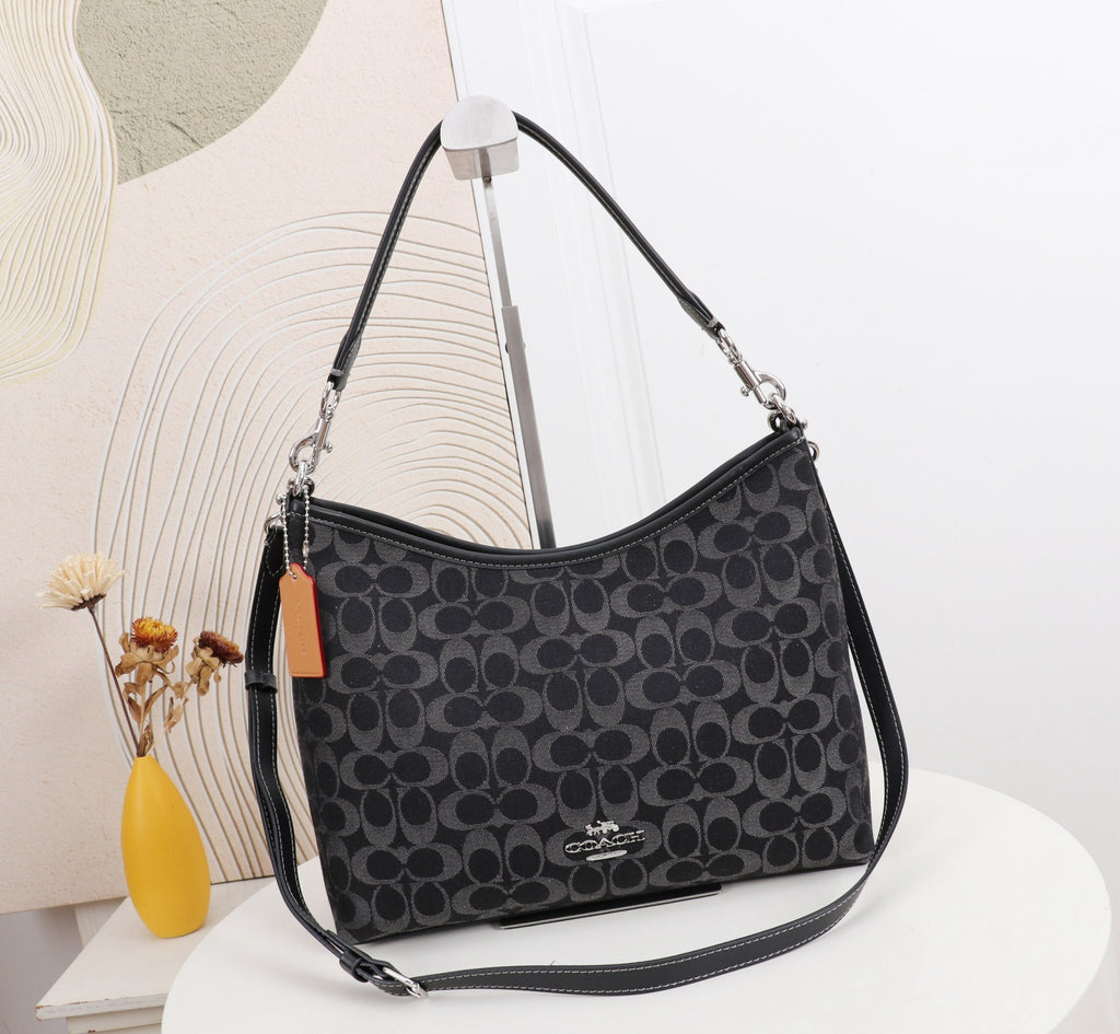 Black patterned handbag with Coach logo on a white surface