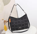 Black patterned handbag with Coach logo on a white surface