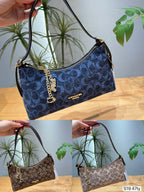 Three views of a Coach shoulder bag in the signature monogram canvas, shown in navy blue, brown, and beige. The handbag features a dark blue and brown monogram pattern, gold-tone hardware, a gold chain charm with a logo, and a black shoulder strap.
