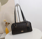 A Coach satchel handbag in their signature dark brown monogram canvas, displayed on a white table with a decorative background.