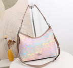A pastel multicolor Coach hobo shoulder bag with a signature monogram pattern, displayed on a white table against a modern beige and white background.