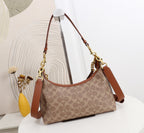 A Coach hobo shoulder bag in the classic monogram canvas, featuring brown leather trim and gold-tone hardware, displayed on a white table with a decorative background.