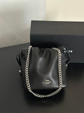 A black Coach shoulder bag with a silver chain strap, displayed in front of its black branded box on a dark surface.