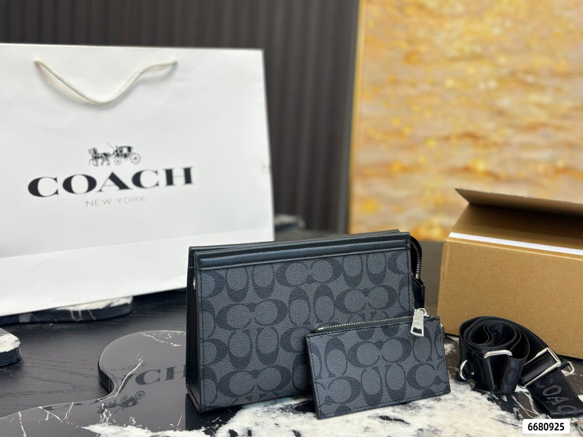 A Coach New York wallet set in the signature monogram canvas, featuring a large rectangular wallet and a smaller zip-around card holder, displayed alongside a white Coach shopping bag, a brown box, and a black strap on a marble surface.