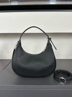 Black handbag with a matching strap on a reflective surface